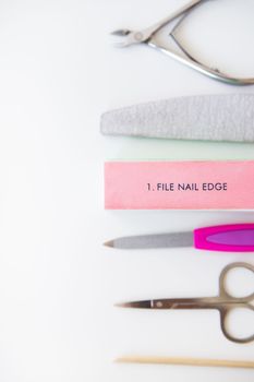 Manicure tools set on a white background. File, buff, scissors, orange stick. Buff with nail file inscription