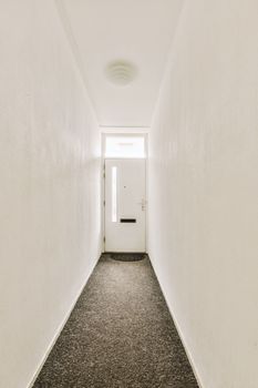 Interior of modern flat in minimal style with narrow empty corridor illuminated by lamps