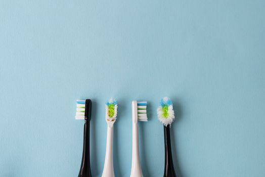 Modern electric toothbrush on a blue background, it's time to change the brush - old and new brush attachment. Hygiene concept for daily oral care