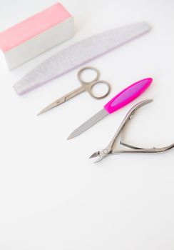 Professional manicure set on a white table. The concept of hand care, salon procedures. File, scissors, buff, bamboo stick, cuticle nippers