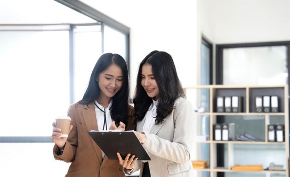 Attractive young asian woman using laptop computer while standing in a office..