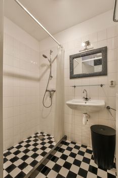 Flush toilet and shower cabin with tile partition and curtain located near sink and mirror in washroom at home