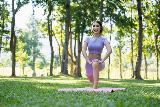 Mature healthy people doing yoga at park. Asian woman exercising on green grass with yoga mat