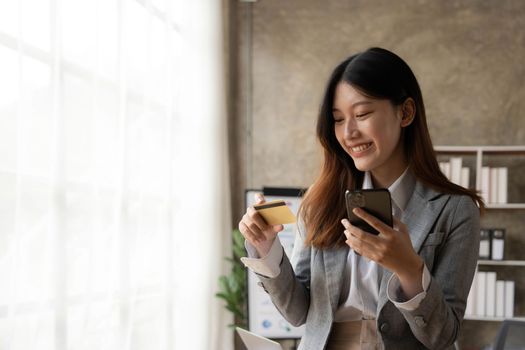 Happy asian Business woman pay online using mobile phone at the office
