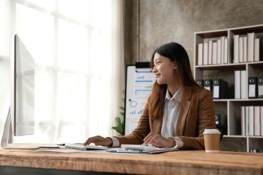 Young woman working on a laptop in the office. Asian businesswoman sitting at her workplace in the office. Beautiful Freelancer Woman working online