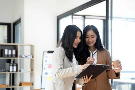 Attractive young asian woman using laptop computer while standing in a office..