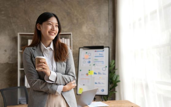 Beautiful Asian businesswoman crossed arms at the office looking at the window..