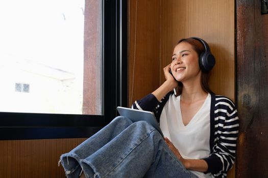 Young attractive asian female with headphone listening music on digital tablet