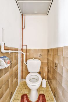 Interior of narrow restroom with wall hung toilet with white walls and checkered floor