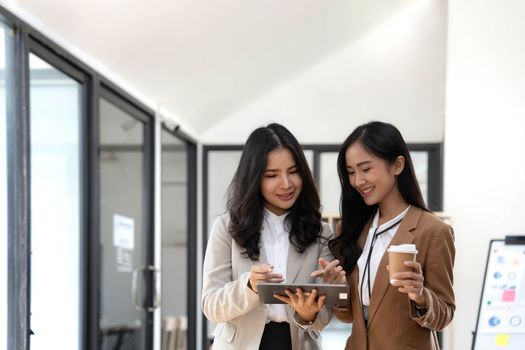 Attractive young asian woman using laptop computer while standing in a office..