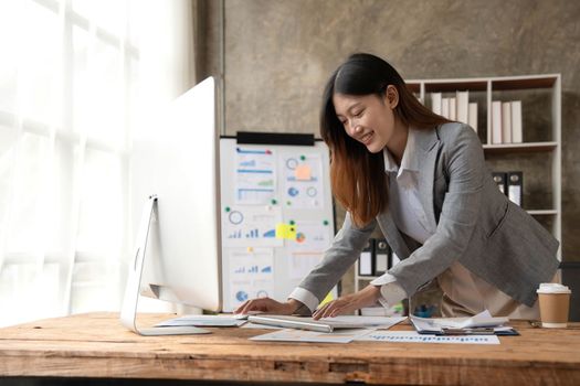 Attractive young asian woman using laptop computer while standing in a office...