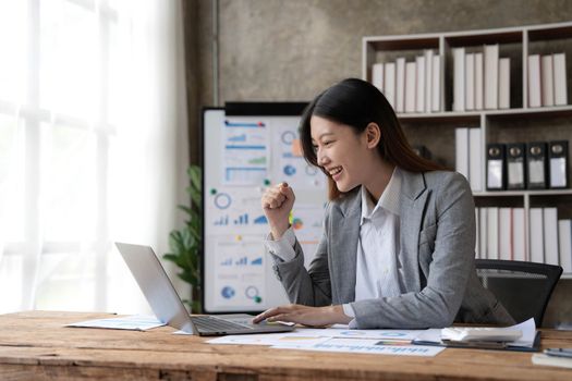 Pretty Asian businesswoman sitting on a laptop And the work came out successfully and the goal was achieved, happy and satisfied with her..