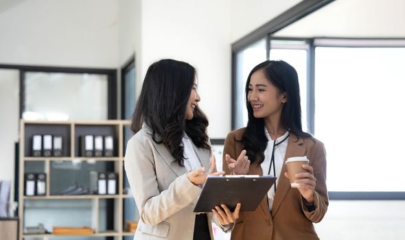 Attractive young asian woman using laptop computer while standing in a office..