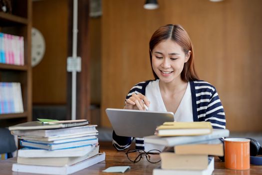 Young asian woman student working on digital tablet in library