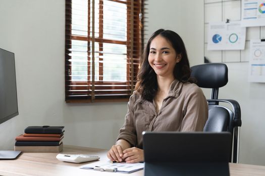 Asian woman accountant preparing annual financial report checking result on calculator bookkeeping. female freelancer counting tax rates declaring income.