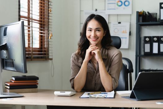 Asian woman accountant preparing annual financial report checking result on calculator bookkeeping. female freelancer counting tax rates declaring income.