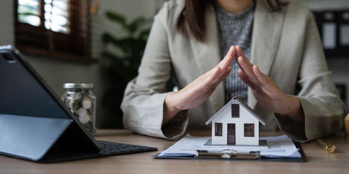 real estate agent use their hands to protect the red roofs, the concept of protecting houses using the gestures and symbols of real estate investors, taking care of credit and contracts...