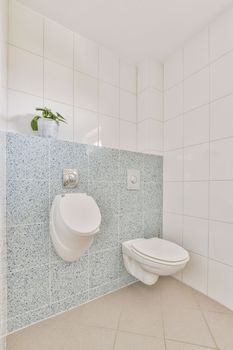 Interior of narrow restroom with wall hung toilet with white walls and checkered floor