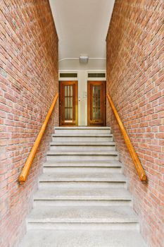 some stairs leading up to the front door on a brick building with wood railings and wooden handrails