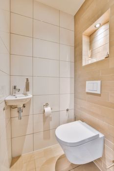 a white toilet in a bathroom with beige tiles on the wall behind it and a sink next to the toilet