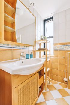 a bathroom with wooden cabinets and white tiles on the floor, in front of a large mirror above the sink