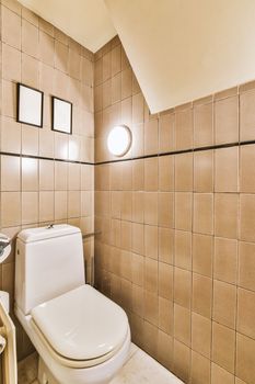 Interior of narrow restroom with sink and wall hung toilet with white walls and checkered floor