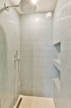 a walk in shower with white tiles on the walls and floor, along with an overhead shower head mounted to the wall