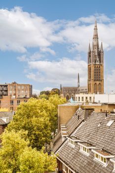 some buildings with a clock tower in the middle part of the photo is taken from an apartment window looking out onto the street