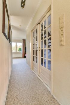 Light narrow hallway with many doors in white walls and glowing lamp over lumber floor