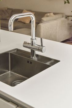 a kitchen sink with water running from the fauced tap in it's right hand held over the sink