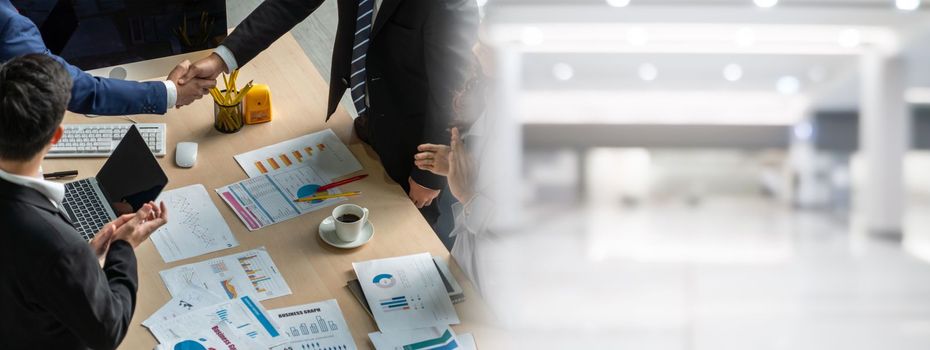 Group business people handshake at meeting table in widen view in office together with confident shot from top view . Young businessman and businesswoman workers express agreement of investment deal.