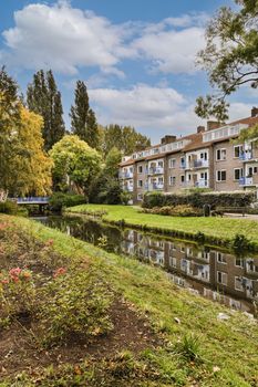 some houses by the water with trees and flowers in the foregrounds on the other side of the river