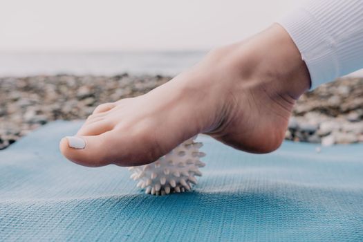 Woman yoga sea. Well looking middle aged woman with braids dreadlocks in white leggings and tops doing stretching pilates on yoga mat near sea. Female fitness yoga routine concept. Healthy lifestyle