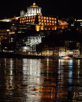 Medieval monastery fort Mosteiro da Serra do Pilar illuminated and douro river with light reflections, Porto old town, Portugal.