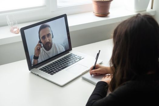 Smiling young teen schoolgirl involved in video web camera call on computer with teacher, listening distant educational lecture in online classroom. homeschooling concept