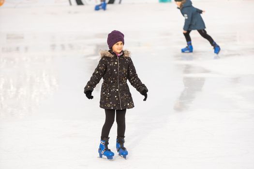 teenage girl ice skating on rink outdoors.