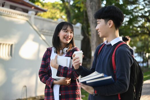 Two smiling college student walking after to college building and discussing the project or sharing the ideas.