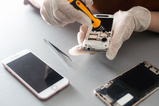 Technician repairing inside of mobile phone by soldering iron. the concept of data, hardware, technology