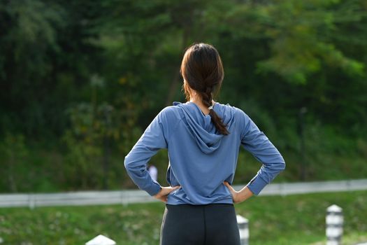 Rear view of female runner resting after sports training outdoors. Fitness, sport and healthy lifestyle concept.