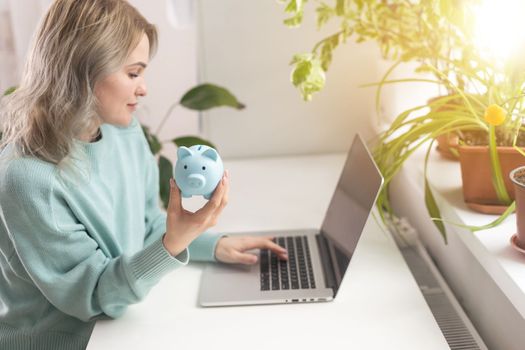 Young woman planning save salary money early years using laptop computer with pig bank save coin