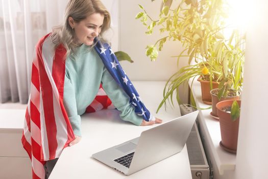 Positive teacher in headset having online lesson on laptop near flags in school.