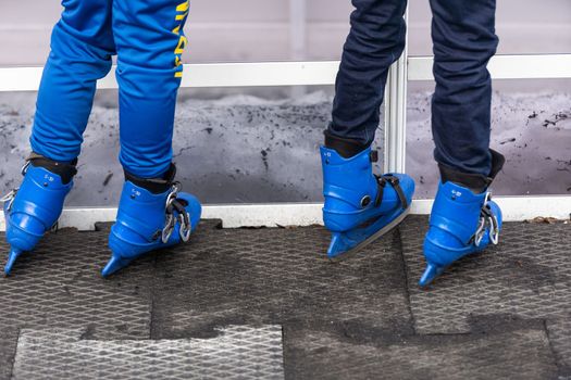 Close-up of family of three wearing skates standing on skating rink they going to skate