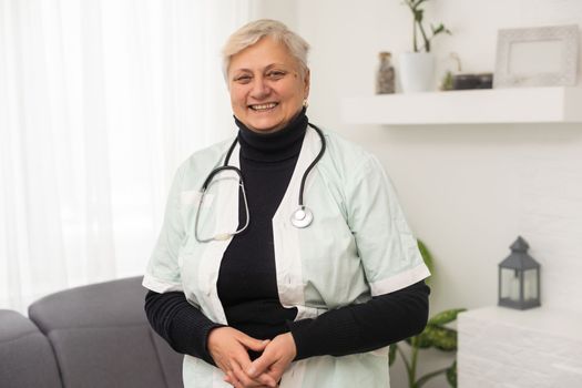 Caucasian senior female doctor confidently with stethoscope around her neck.