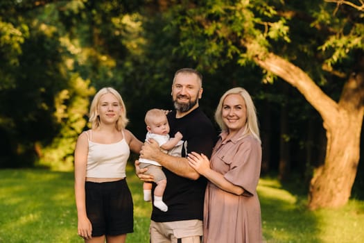 Happy family in the park of four people in the summer in the park in nature.