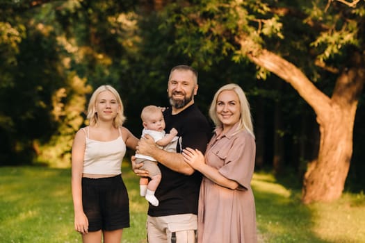 Happy family in the park of four people in the summer in the park in nature.