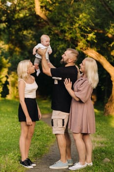 Happy family in the park of four people in the summer in the park in nature.