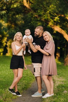 Happy family in the park of four people in the summer in the park in nature.