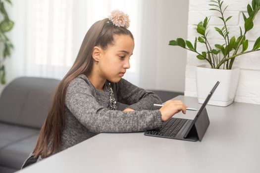 school kid girl student using digital tablet looking at screen at desk. Online education, virtual classes software tech ads.