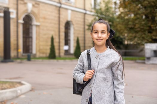 Preteen girl child with backpack outdoors. Pretty schoolgirl going home after class.