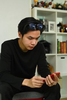 Young man using smart phone while sitting on couch.